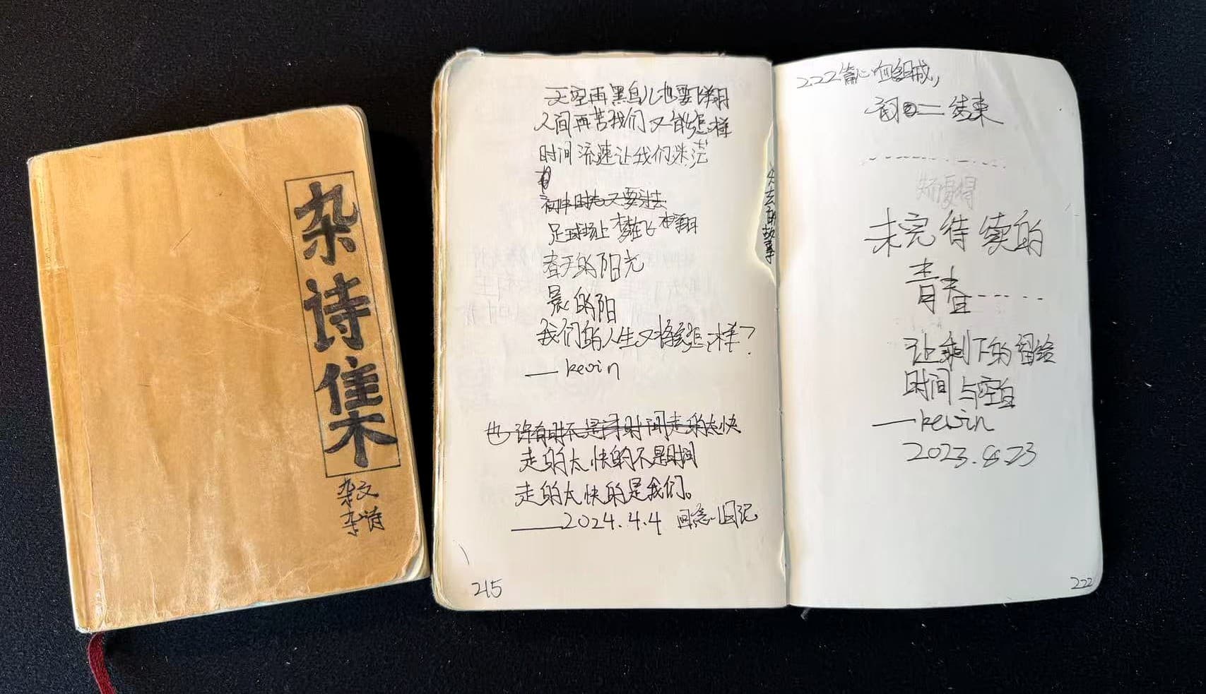 深色桌面上摆放着磨损的《杂诗集》和一本摊开的手写诗稿